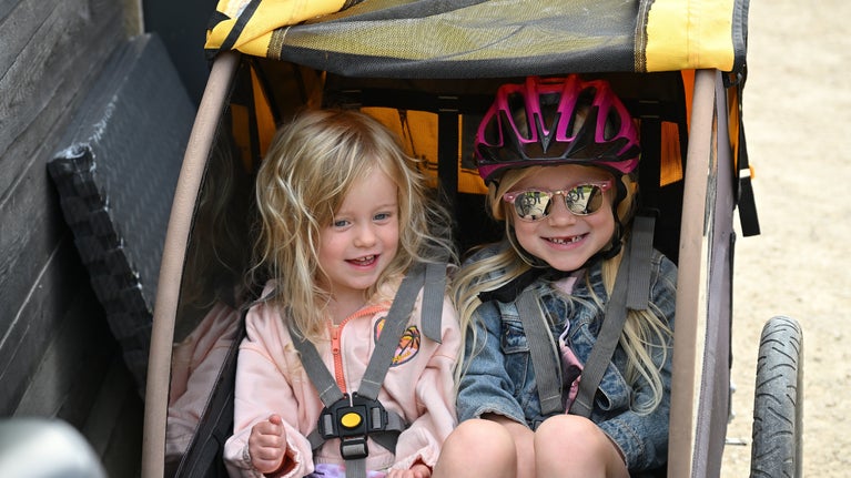 Two children sat in a cycling trailer
